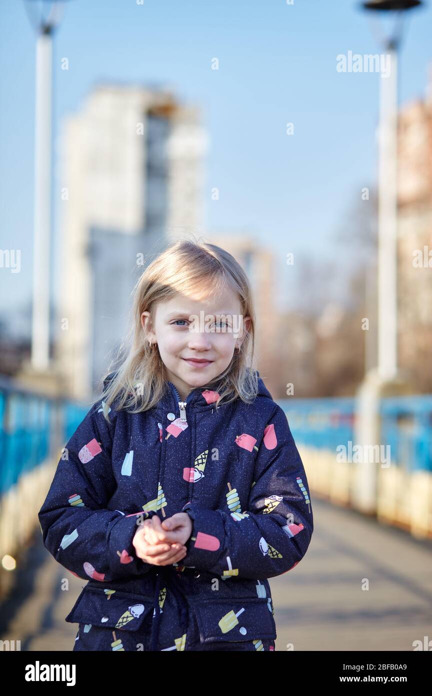 Cheerful child in blue jaket posing outdoors. Caucasian young girl enjoys a bright spring lifestyle Stock Photo