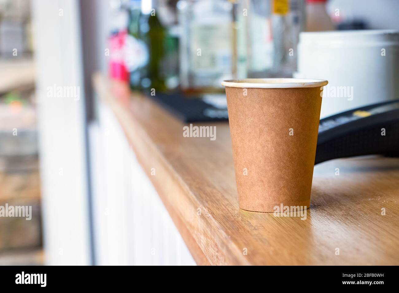 A disposable coffee cup made of recycled paper on coffee shop counter. Stock Photo