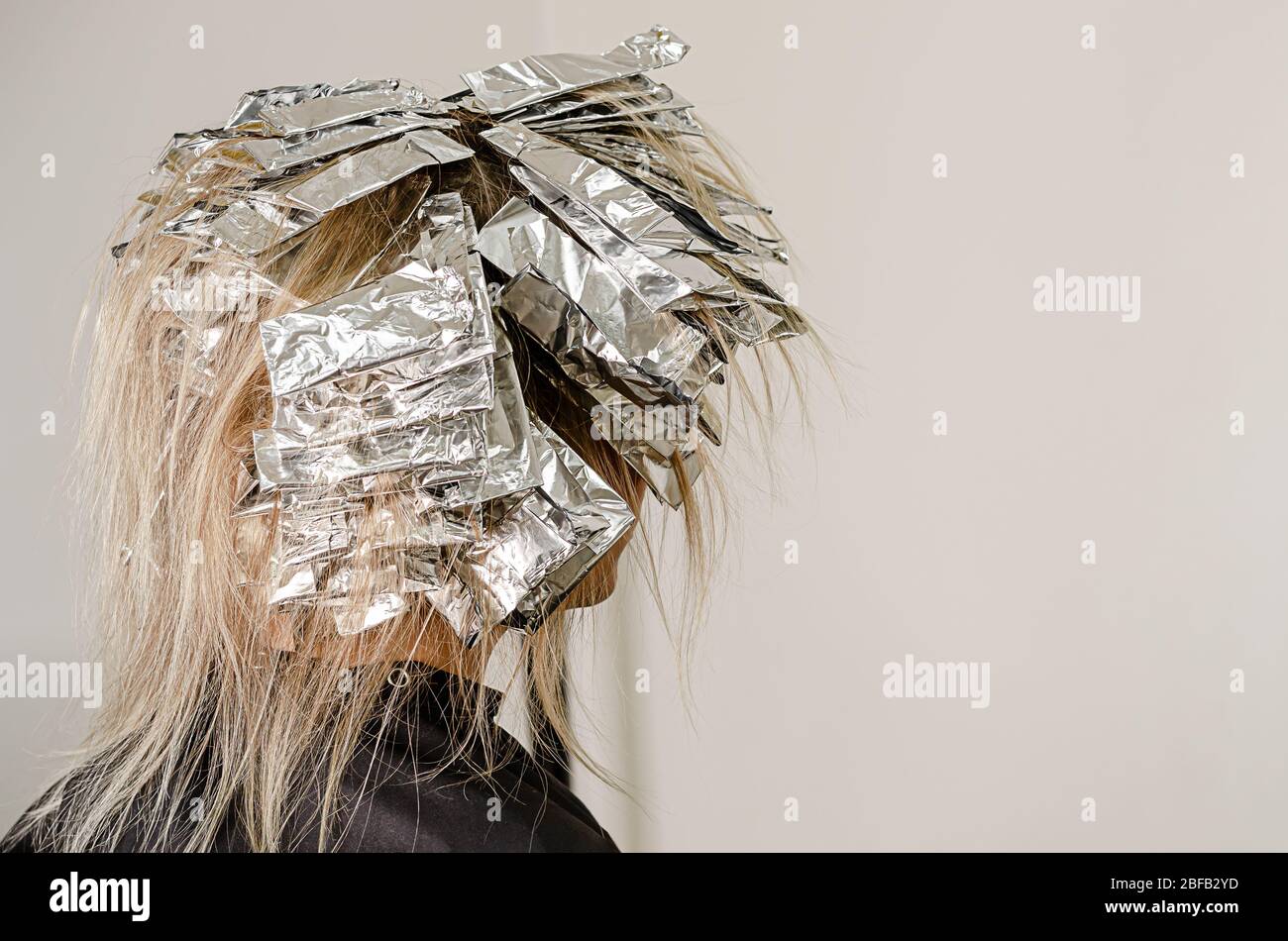 Foil on models hair. Bleaching or dyeing process. Beauty salon