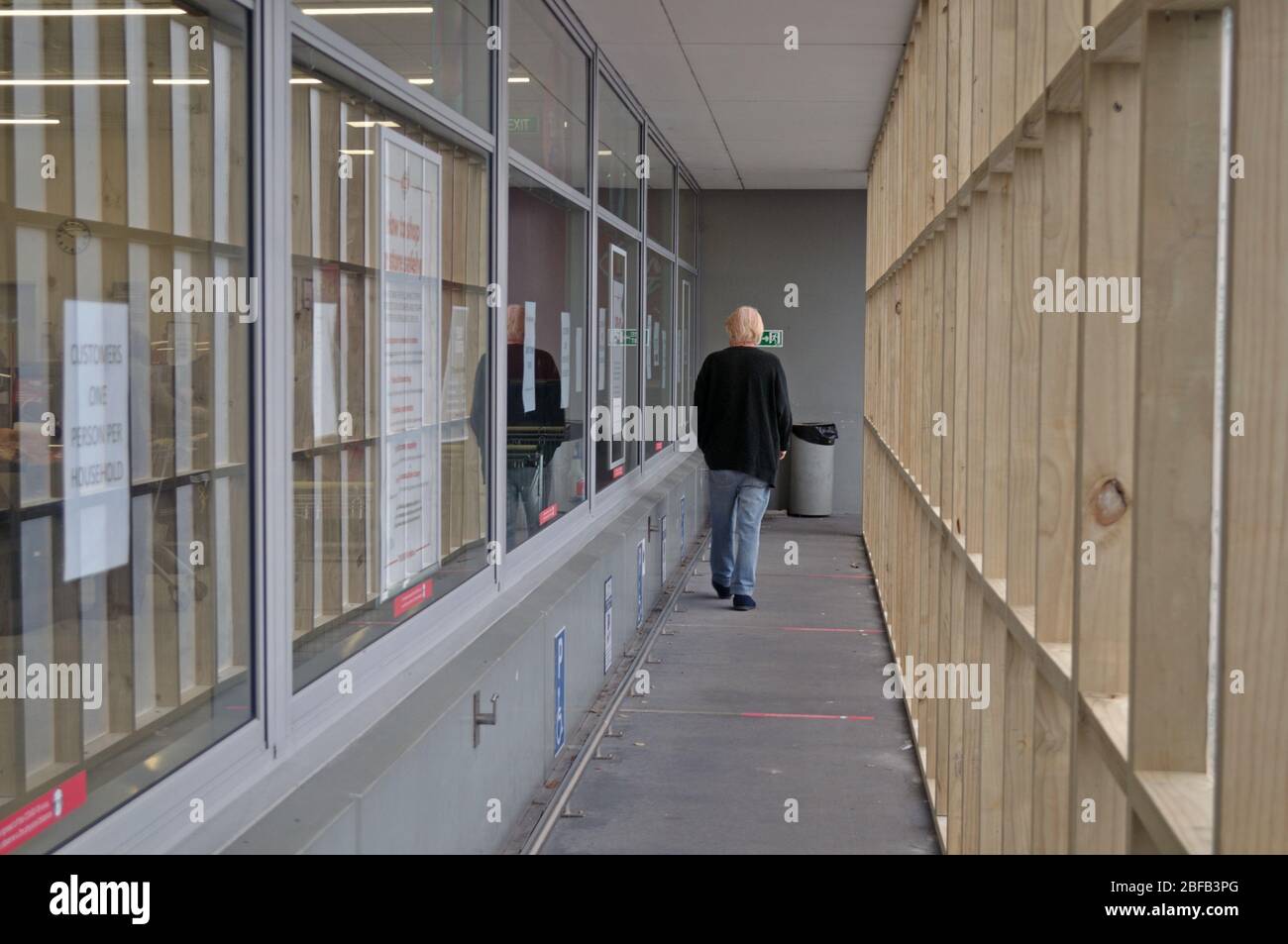 GREYMOUTH, NEW ZEALAND, APRIL 11, 2020: A customer walks through a temporary entrance to create social distancing at a supermarket during the Covid 19 lockdown in New Zealand, April 11,  2020. The red strips on the floor are spaced two metres apart. Stock Photo