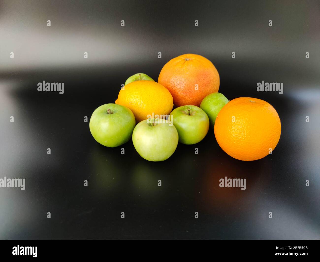 Whole fruits green apples, orange, grapefruit and lemon on black background. Concept - vegetarian and healthy food to improve the immunity Stock photo Stock Photo