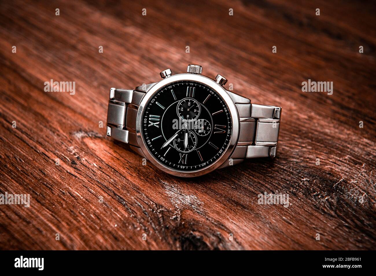 Metal luxury wrist watch on a brown wooden table Stock Photo