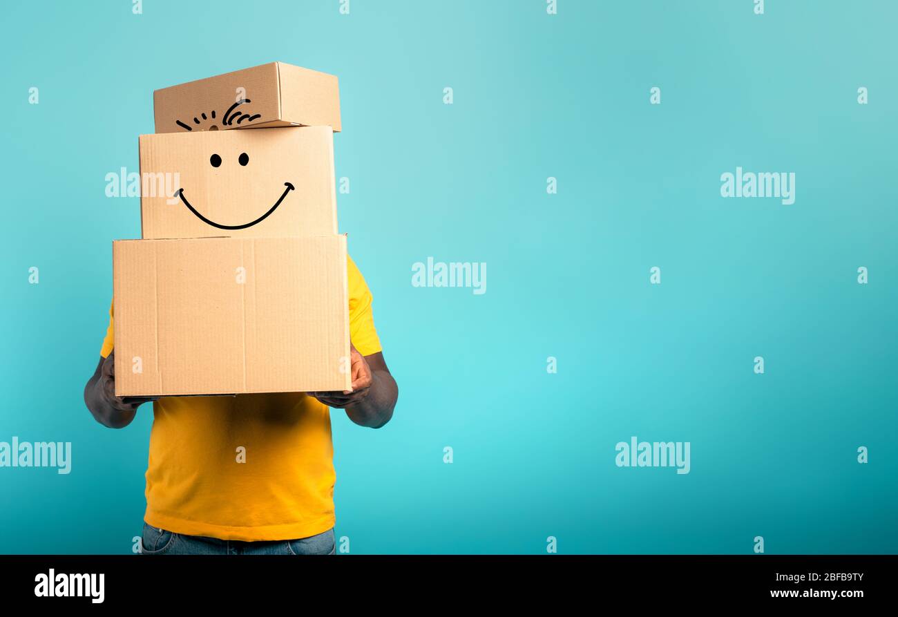 Man is hidden by too many received packages. Cyan background Stock Photo