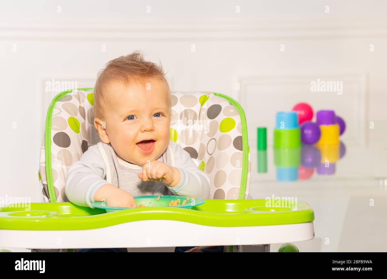 Toddler boy sit in high chair show laughing face and open mouse play