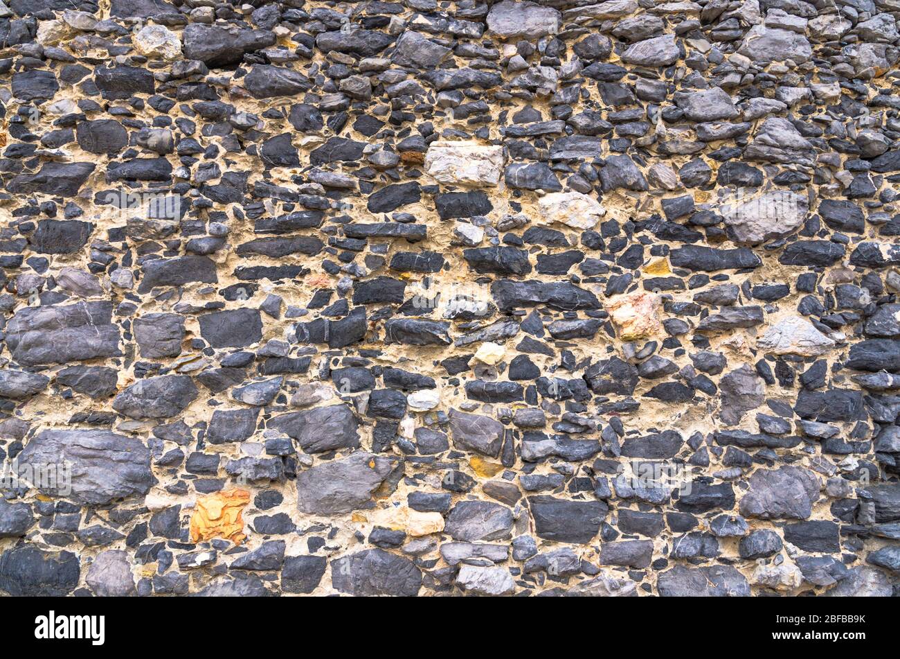 Black stone old ancient wall background with copy space. Abstract old close-up texture. Patterned view. Stock Photo