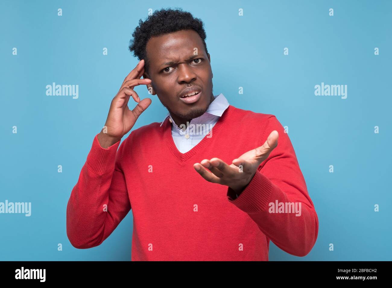 Pensive young african man against a blue background Stock Photo