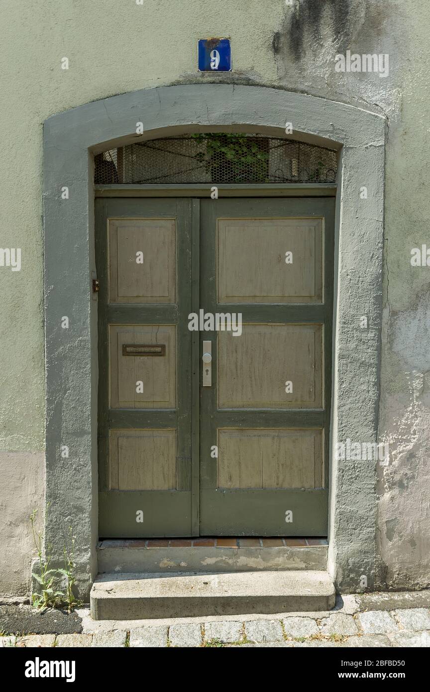 green wooden door with cassettes in old walls with slanted walls Stock Photo