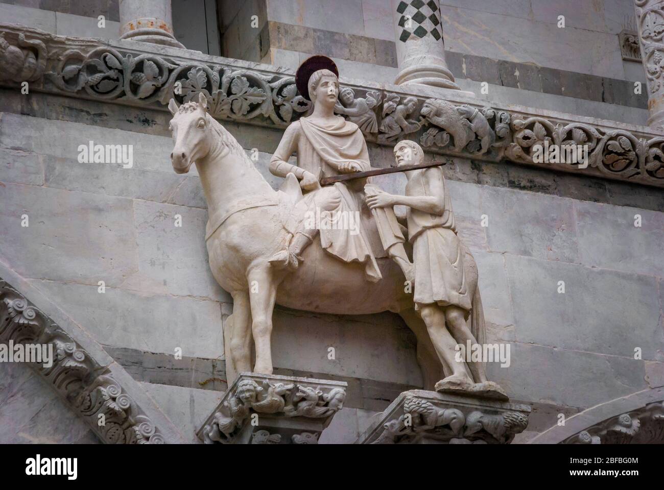 Saint Martin and the beggar, ca. 1200, Statue on the Facade of St. Martin Cathedral in Lucca, Tuscany, Italy Stock Photo