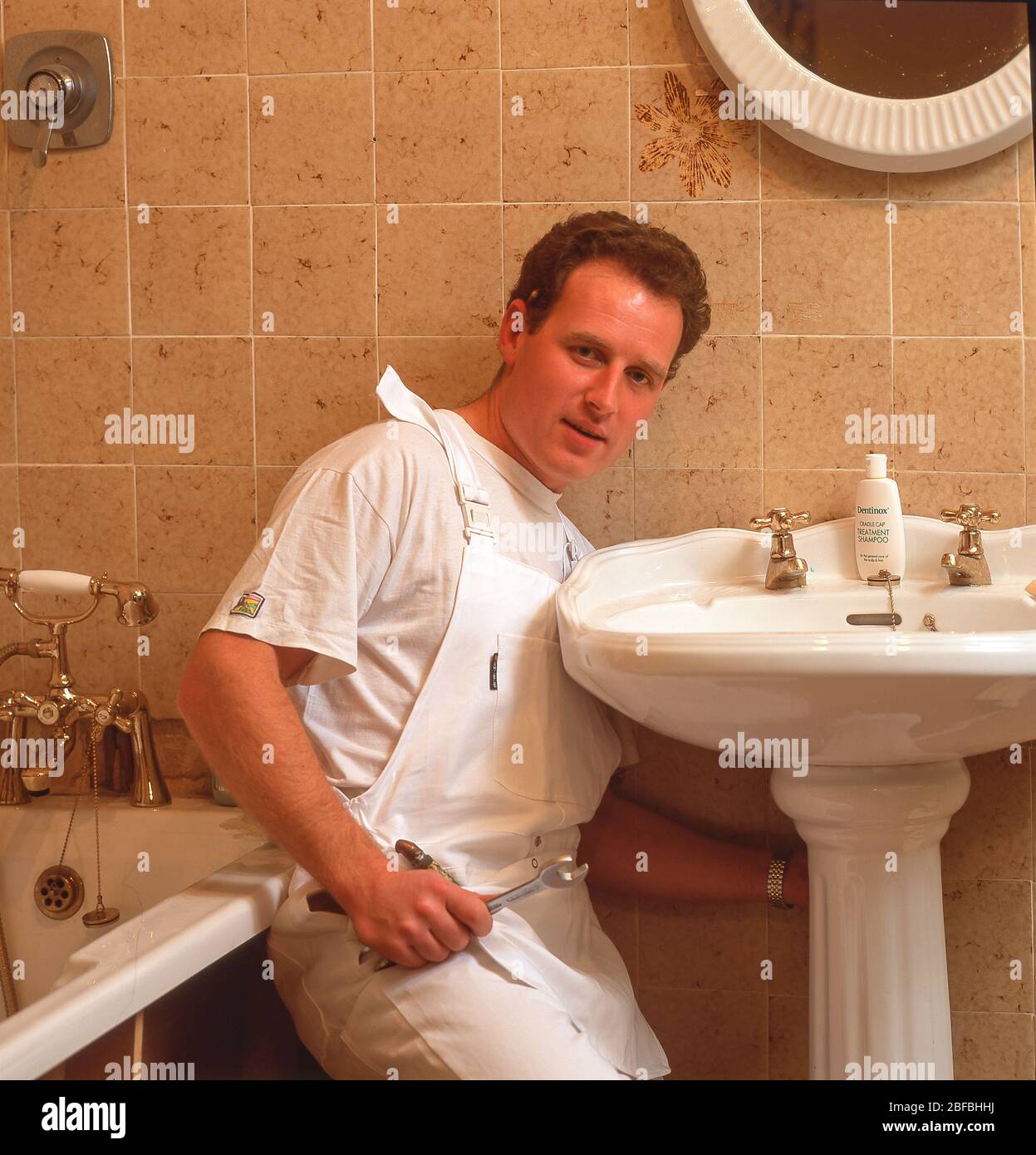 Plumber fitting sink in bathroom, Winkfield, Berkshire, England, United Kingdom Stock Photo