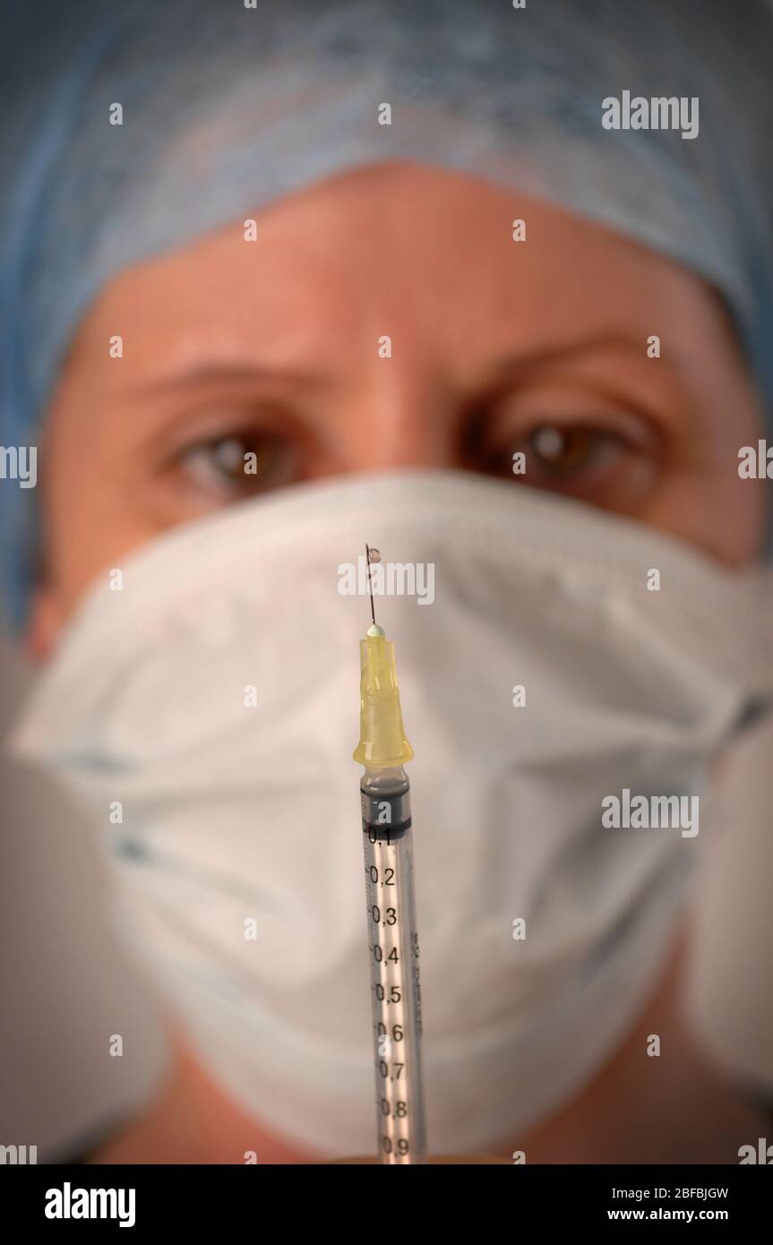 A hospital worker analyses a dripping syringe Stock Photo