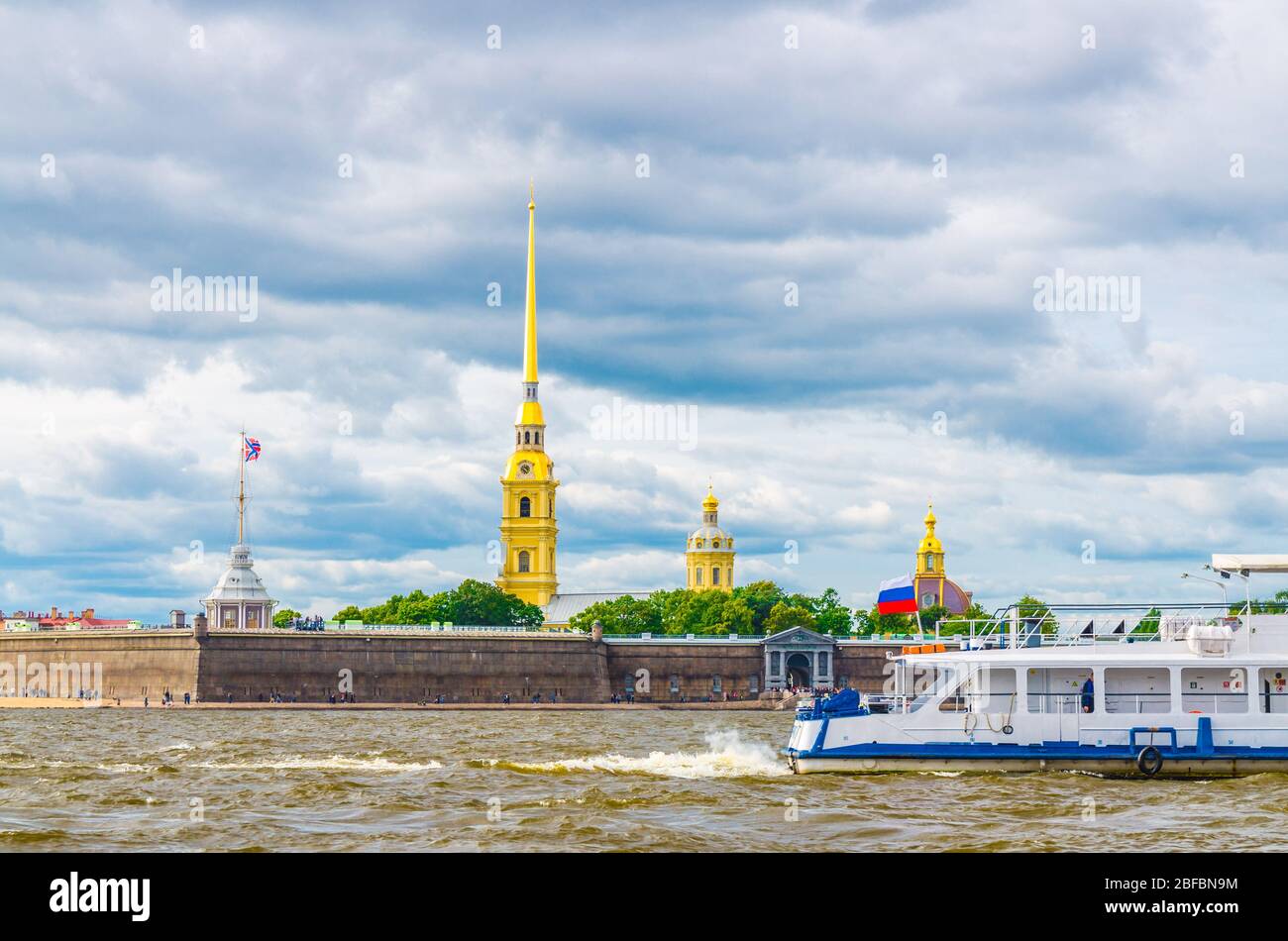 The Peter and Paul Fortress citadel, Saints Peter and Paul Cathedral with gold spire, fortress walls on Zayachy Hare Island, touristic boat ship on Ne Stock Photo
