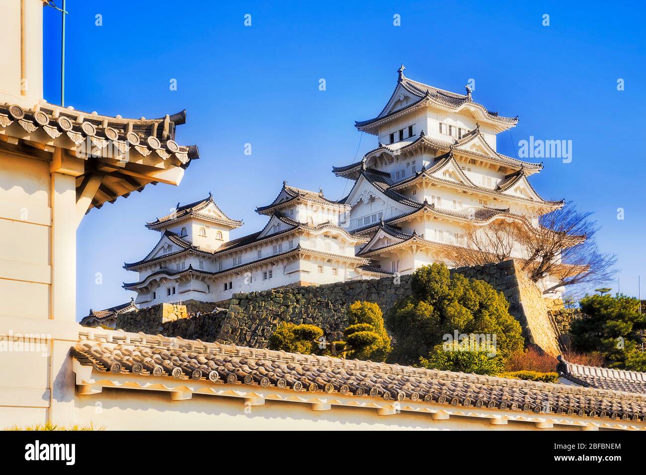 Main white tower and palace over tall stone walls in Himeji park - traditional japanese architecture. Stock Photo