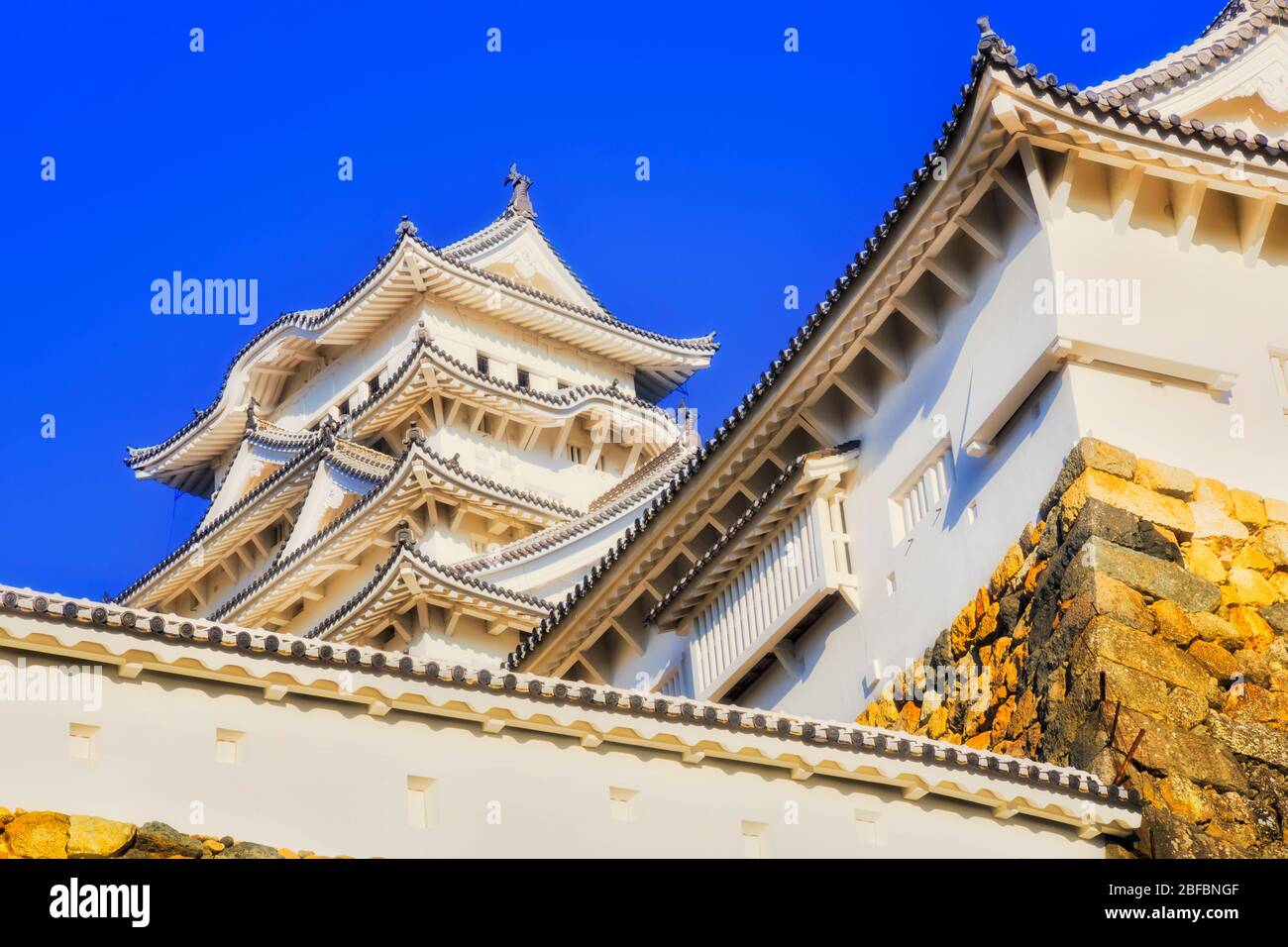 Geometry of tall white towers and traditional japanese roofs with beams - historic Himeji castle. Stock Photo