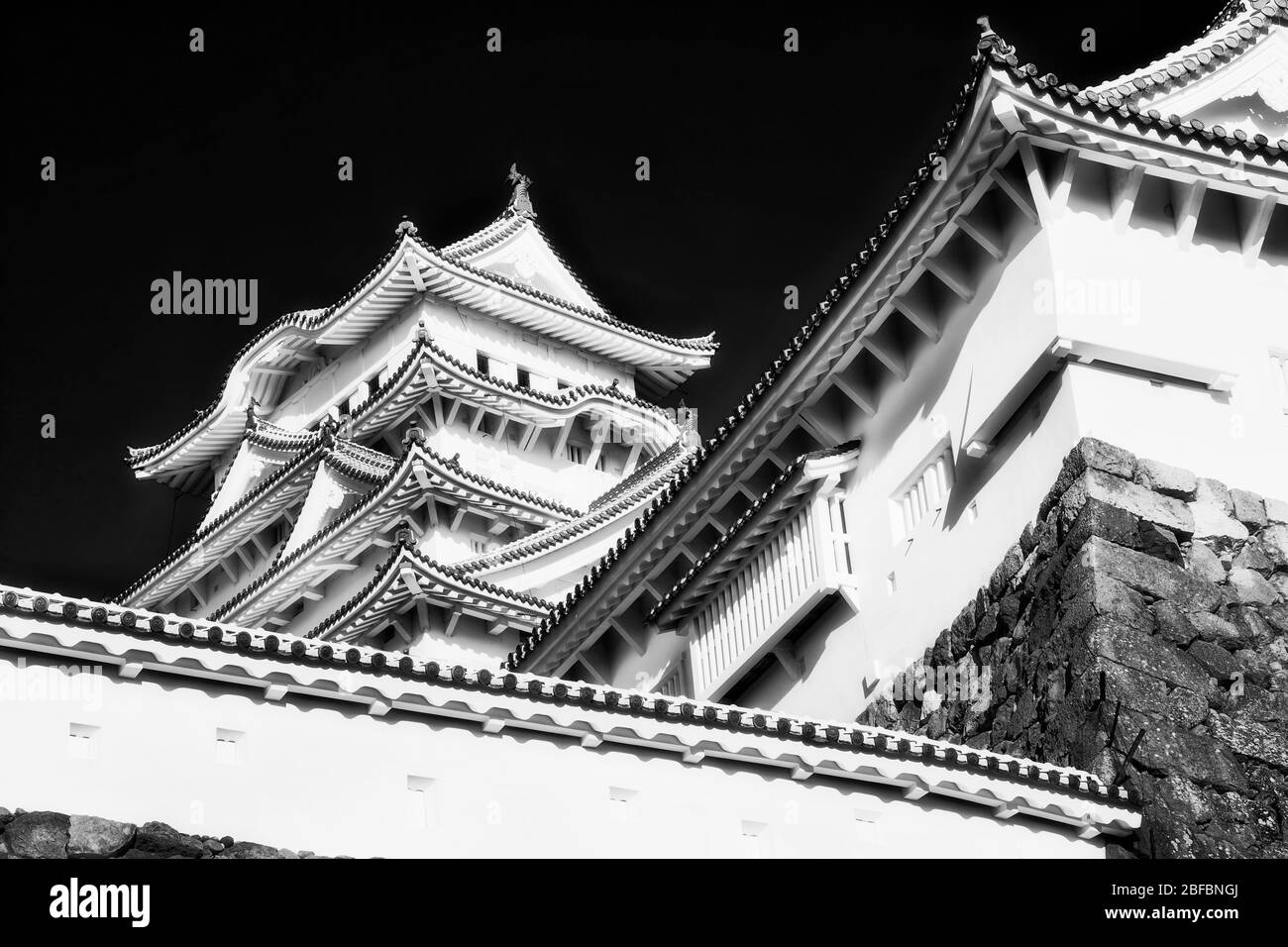 Black-white shapes of tall white towers and traditional japanese roofs with beams - historic Himeji castle. Stock Photo