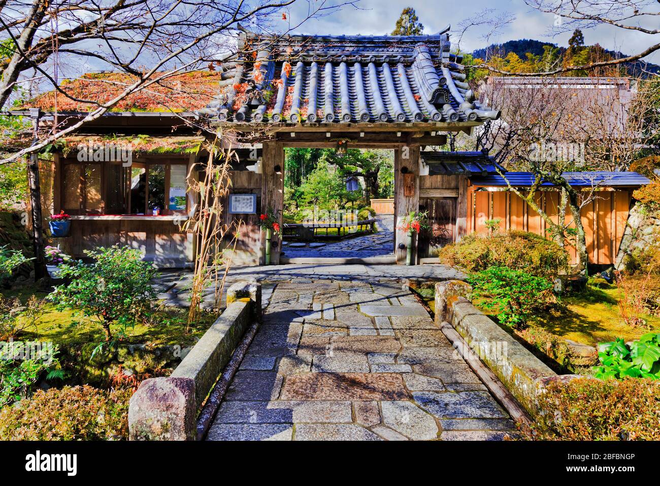 Traditional japanese garden through open historic gate with roof beams and tiles in ancient rural village Ohara near Kyoto. Stock Photo