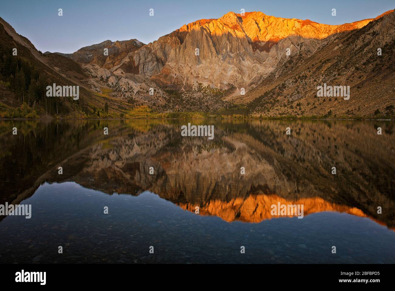 First light autumn glow reflection of the Eastern Sierra Mountains at California’s Convict Lake and Mono County. Stock Photo