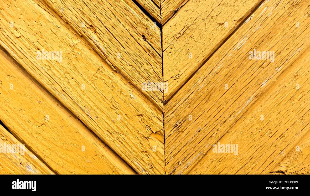 Yellow wood door with centered symmetrical direction decoration. Colored wooden textured