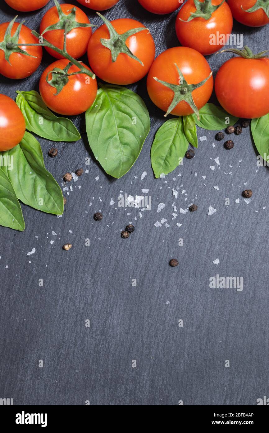 Cherry tomatoes and basil leaves on black background Stock Photo