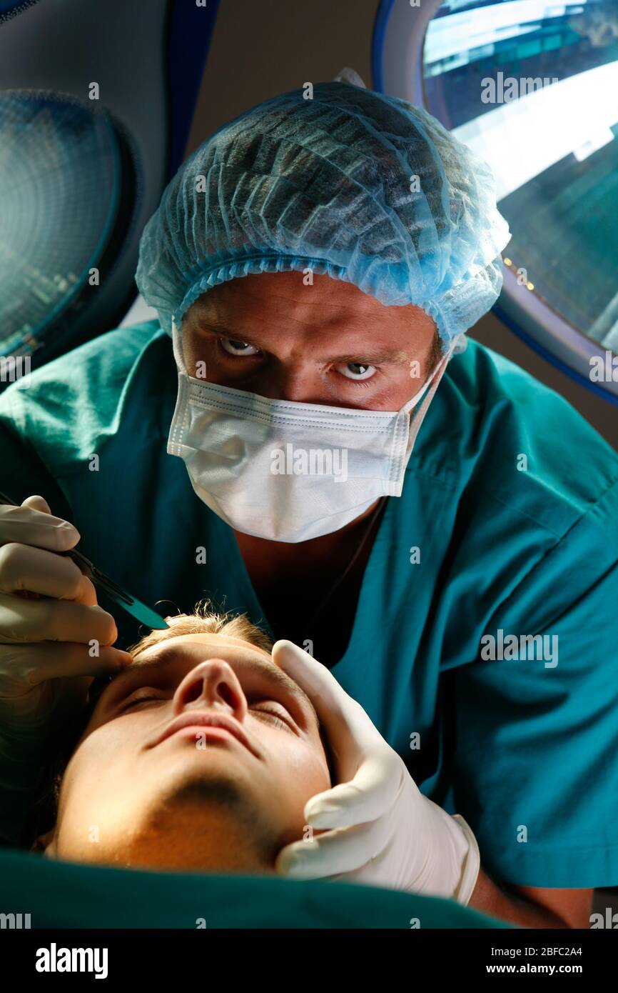 A surgeon prepares to makes a surgical incision into the forehead of a patient. Stock Photo