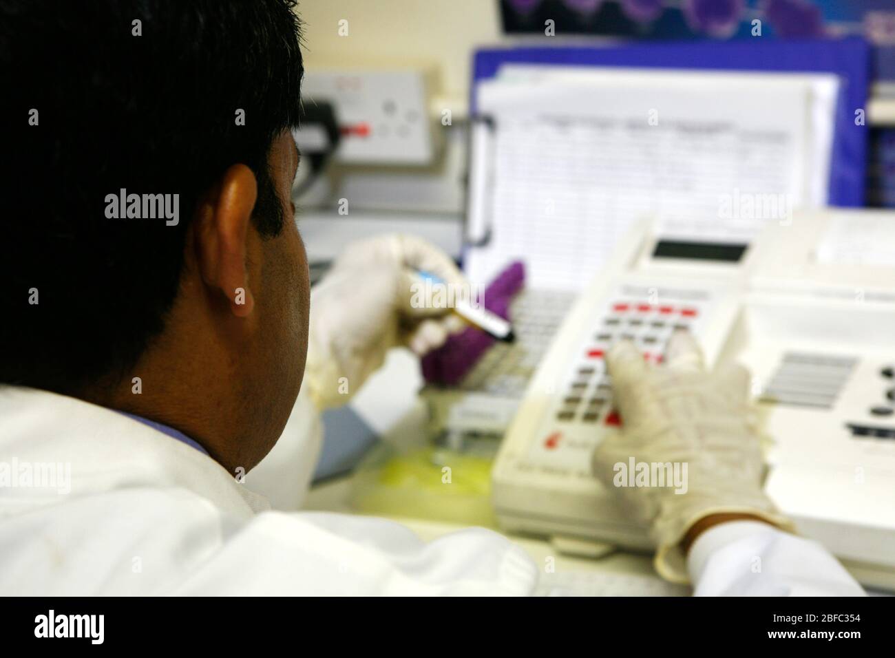 A pathologist manually inputting the data from the bar code on a tube of blood. The bar code is used as a way of individually identifying  blood sampl Stock Photo