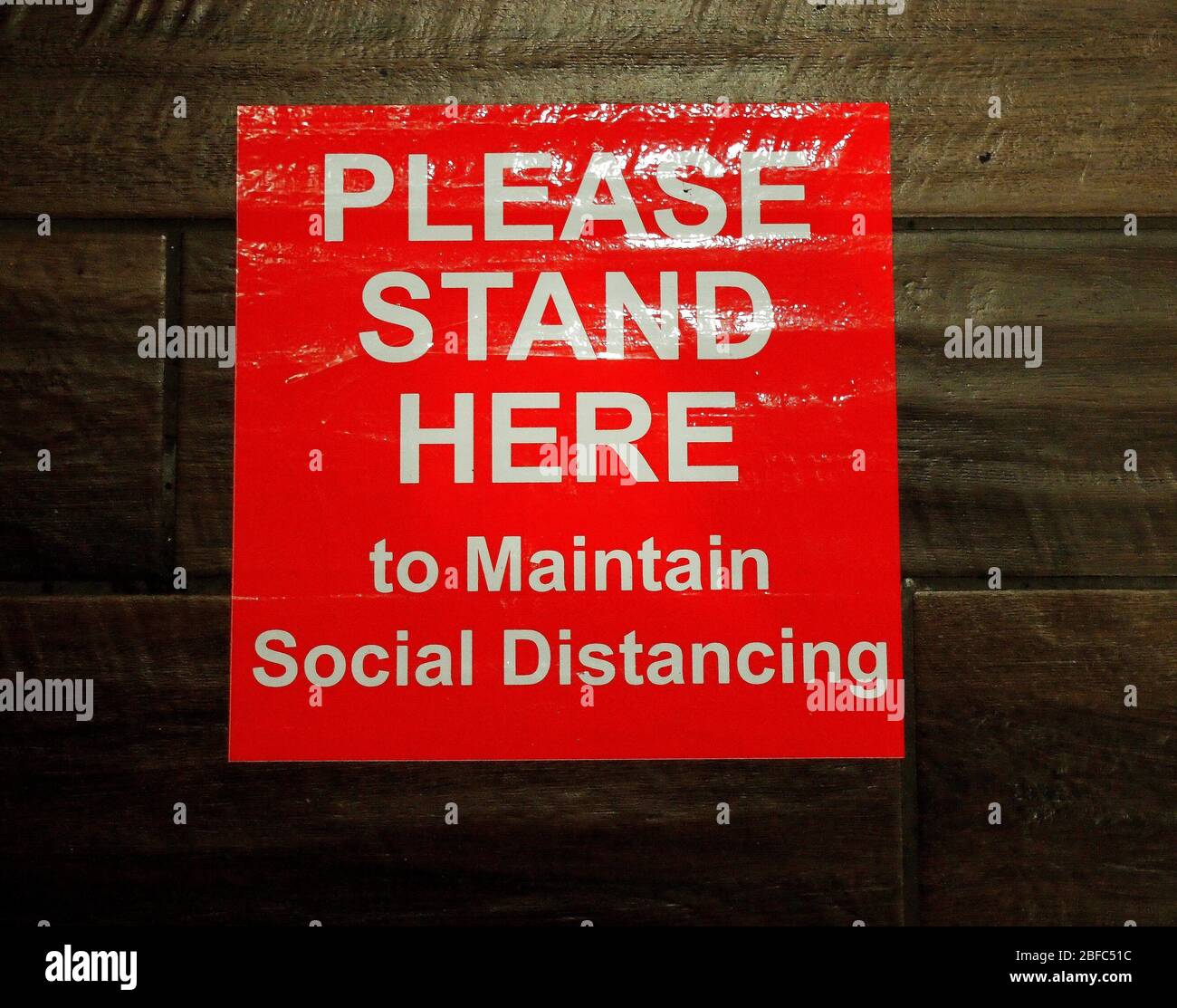 PLEASE STAND HERE to maintain social distancing marker on bank's floor in California Stock Photo