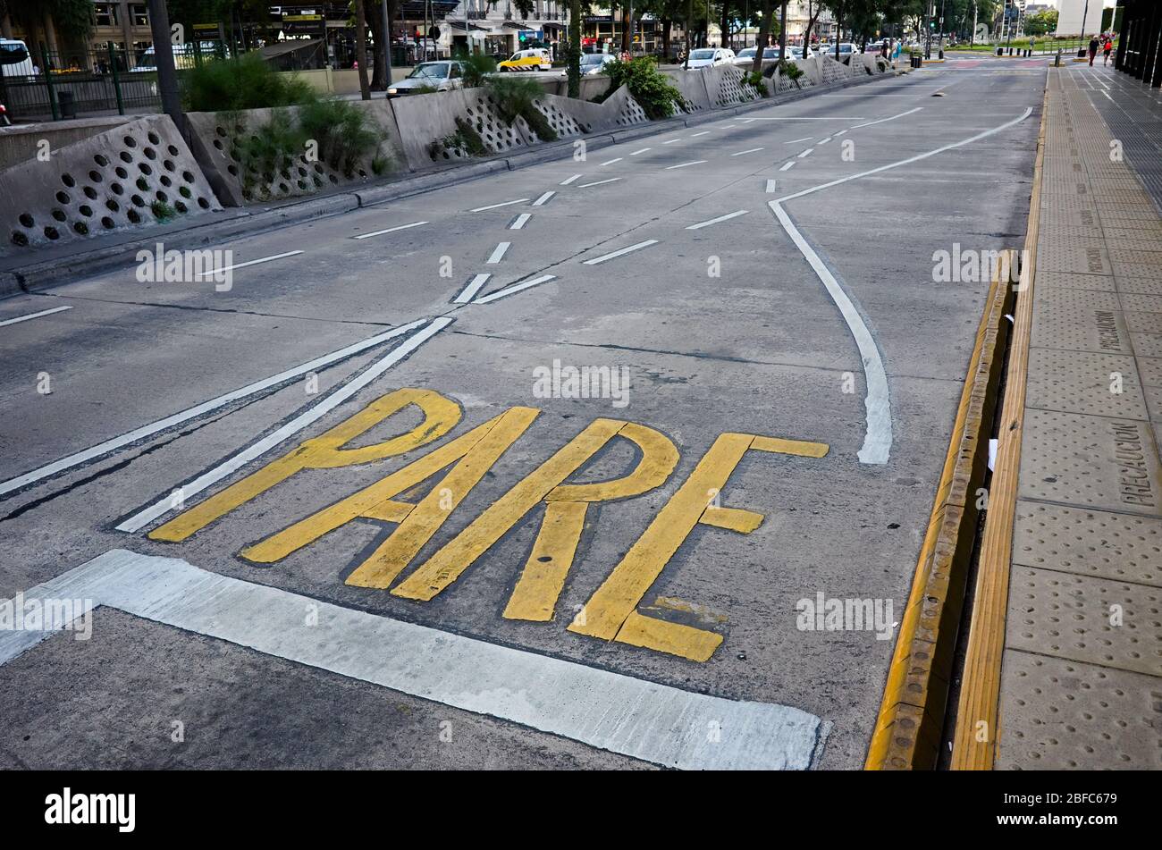 Yellow stop sign painted on asphalt on the road near other white traffic lines. Pare sign on Spanish means Stop. Buenos Aires, Argentina. Stock Photo