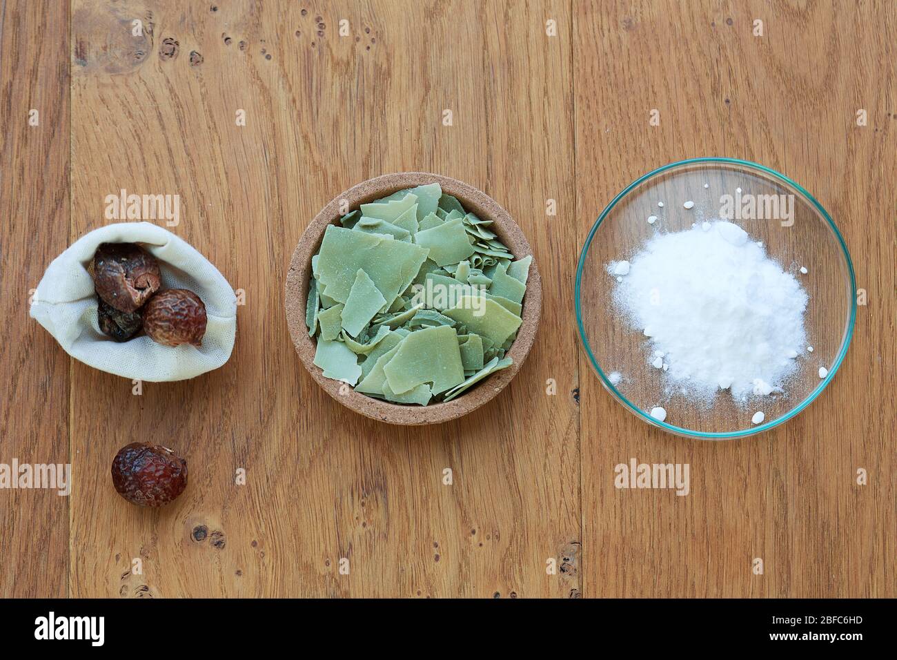 Flat lay overhead shot of Aleppo soap, baking soda and accessories for laundry like soapberries on a wooden background. Flat lay overhead shot of an A Stock Photo
