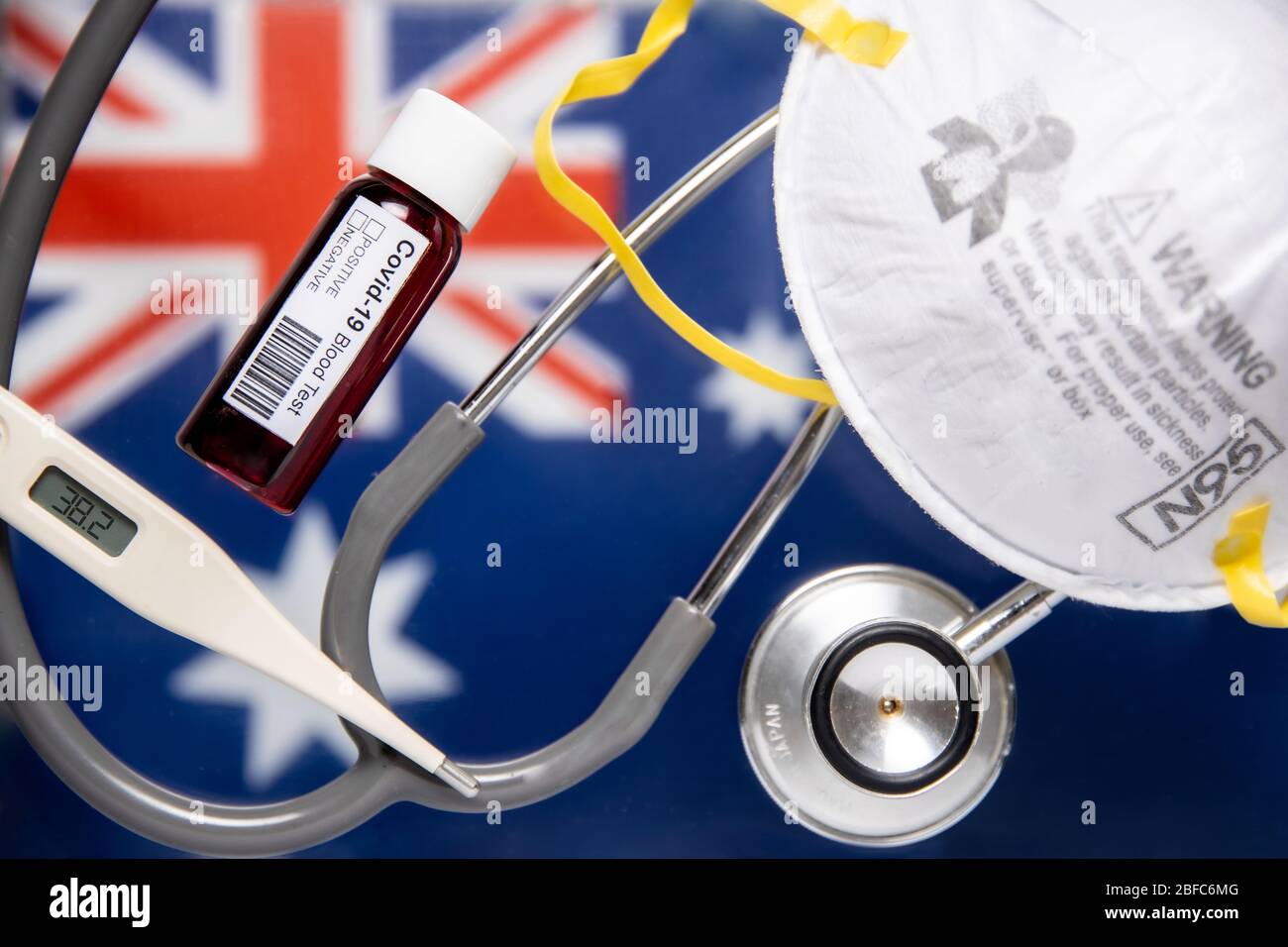 Concept of Coronavirus or Covid-19 pandemic background with Australia Australian country flag and medical blood test, stethoscope, surgical M95 Mask Stock Photo