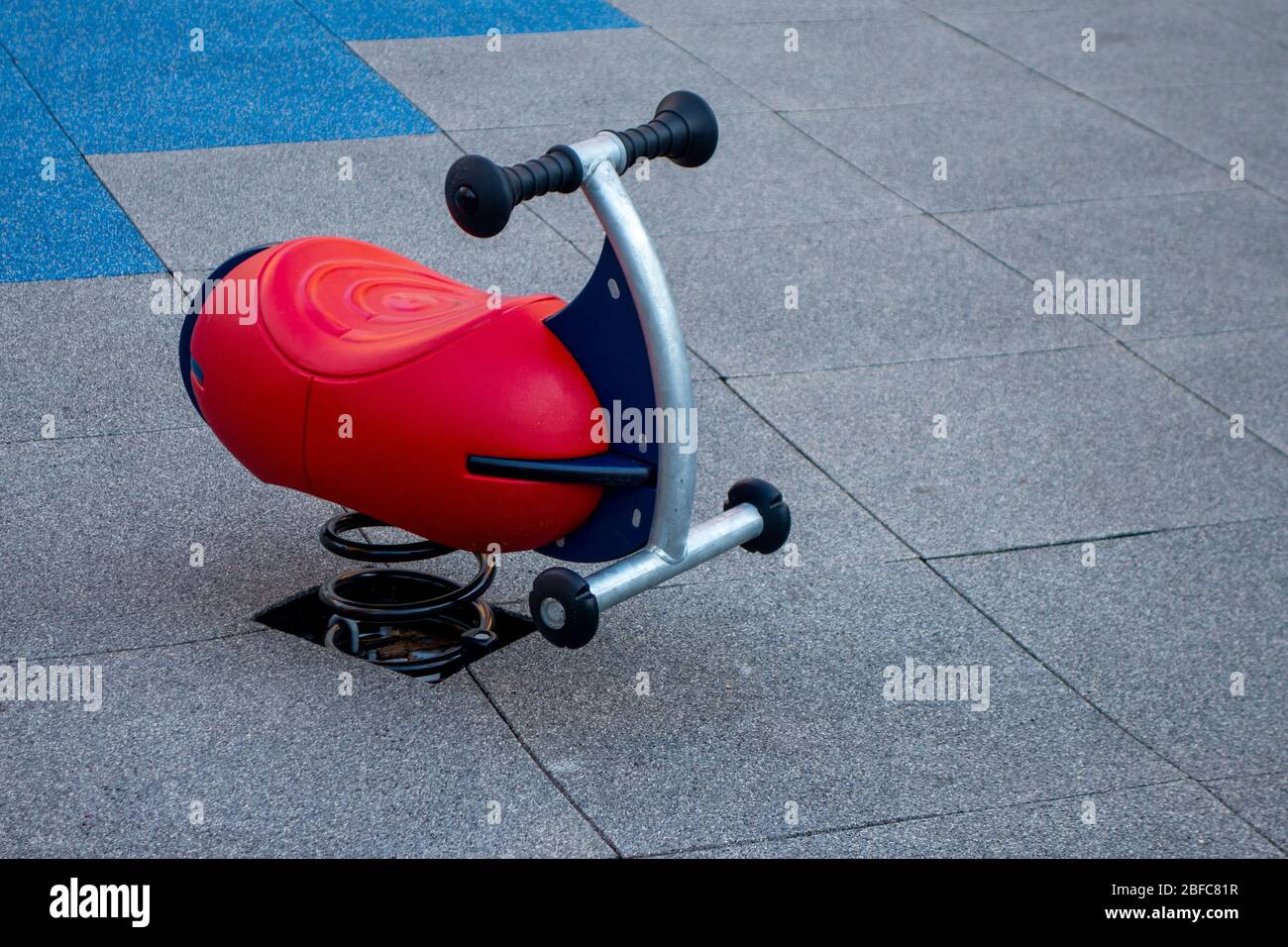 rocker toy rider in a children's public playground with rubber tiled mats Stock Photo