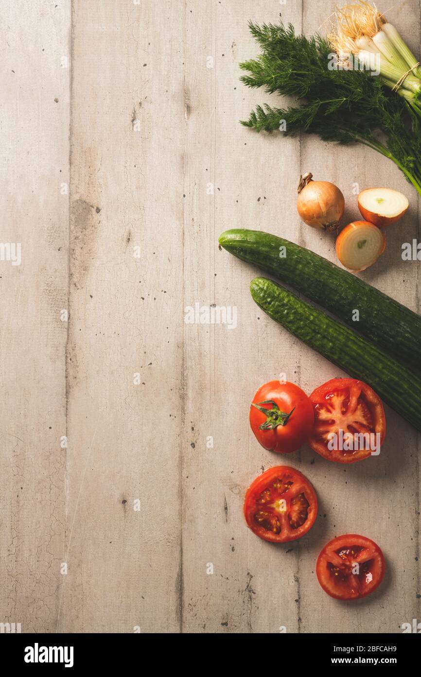 Fresh cucumbers, tomatoes onions and dill on a light color wooden background Stock Photo