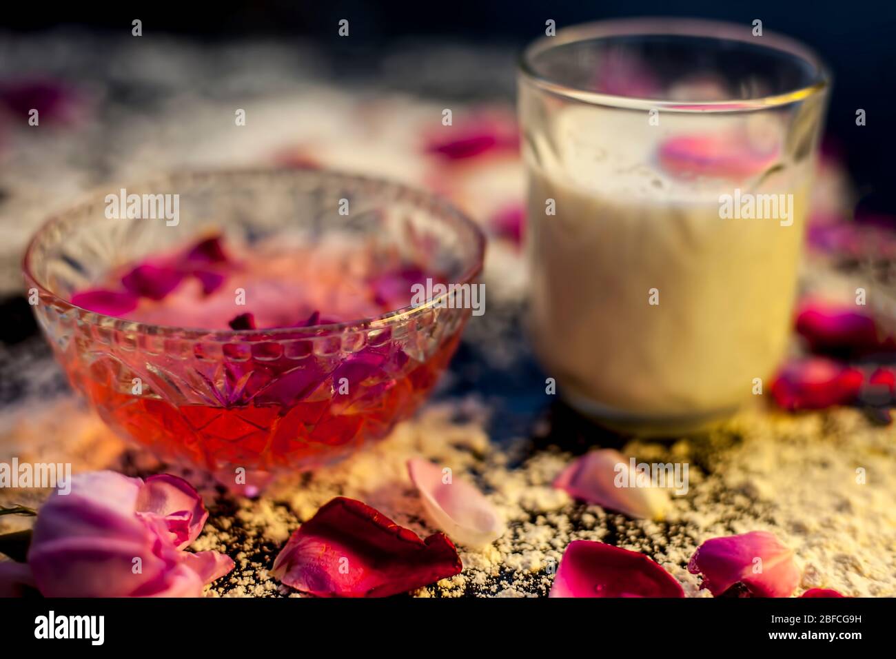 Wheat flour face mask for oily skin on a black colored board consisting of  some rose water, milk, wheat flour and raw honey for oily skin. Shot of all  Stock Photo -