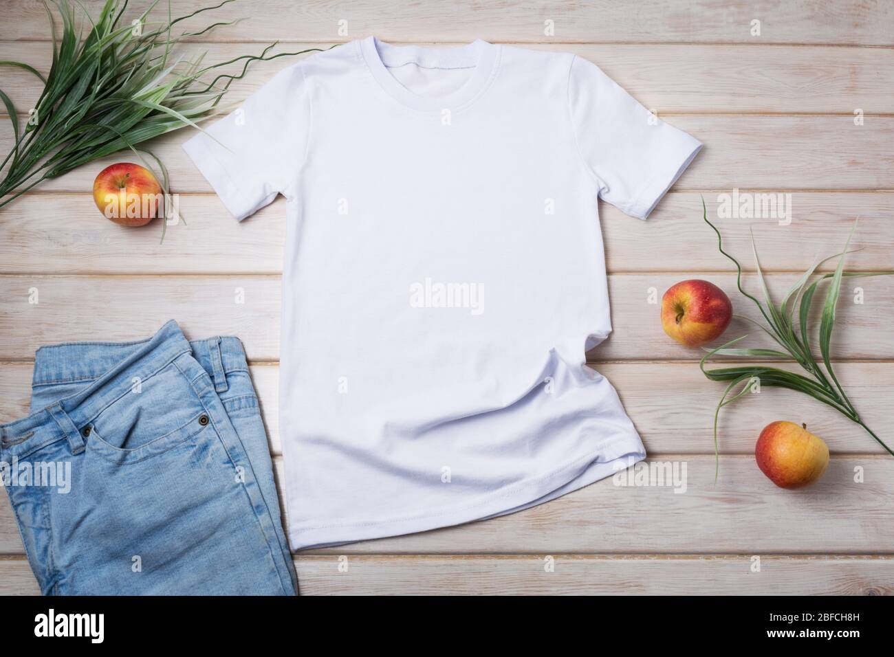 White unisex cotton T-shirt mockup with green grass and apples. Design t shirt template, tee print presentation mock up Stock Photo