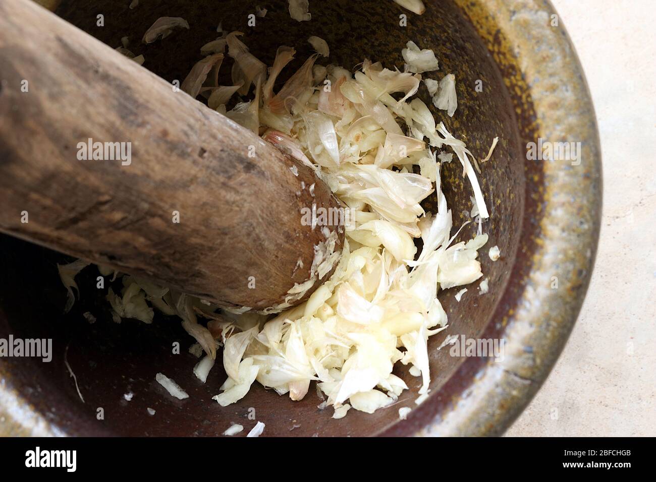 A picture of garlic that has been pounded. In a mortar with pestle