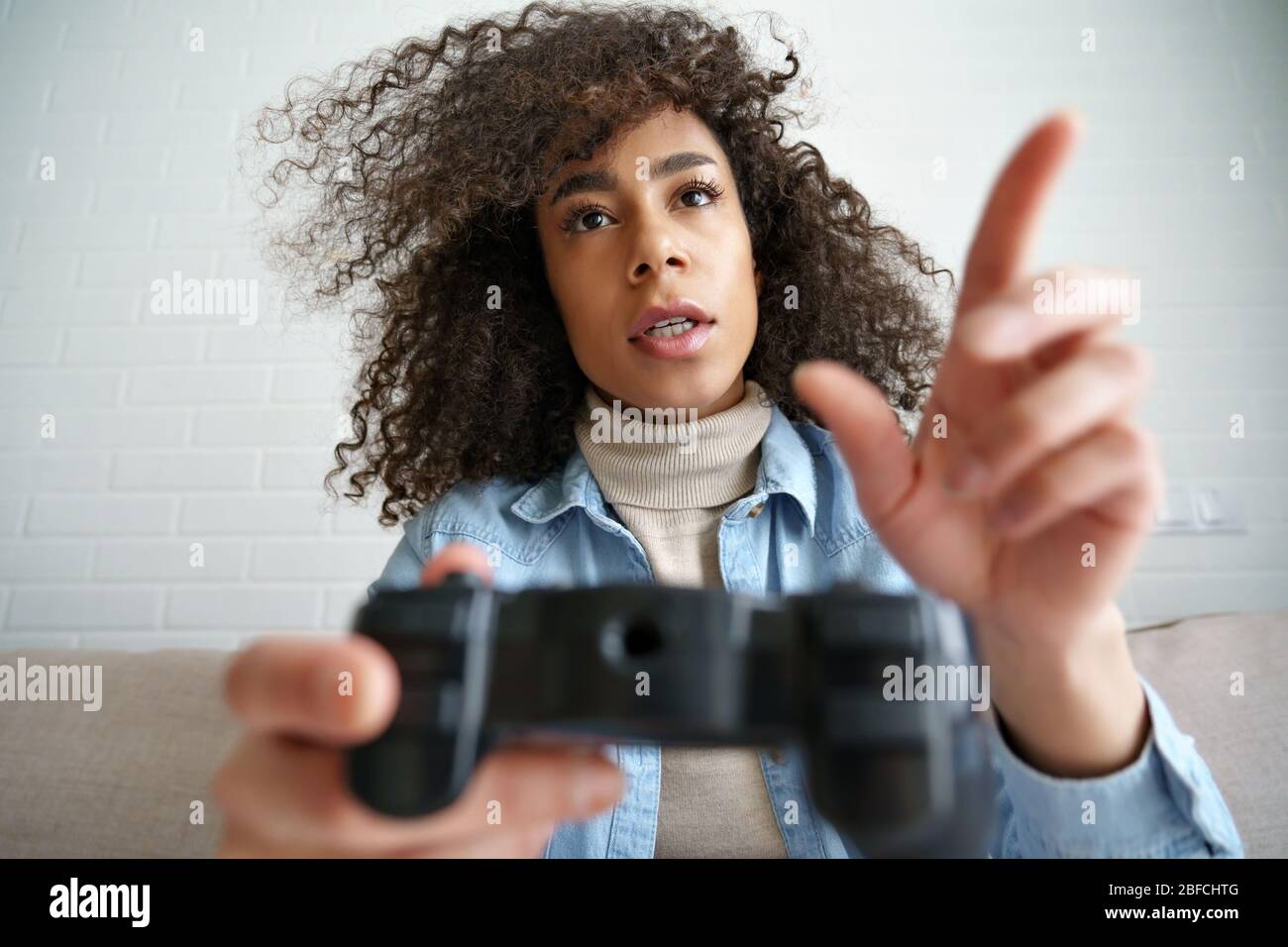 Young african girl gamer holding joystick controller playing video game. Stock Photo