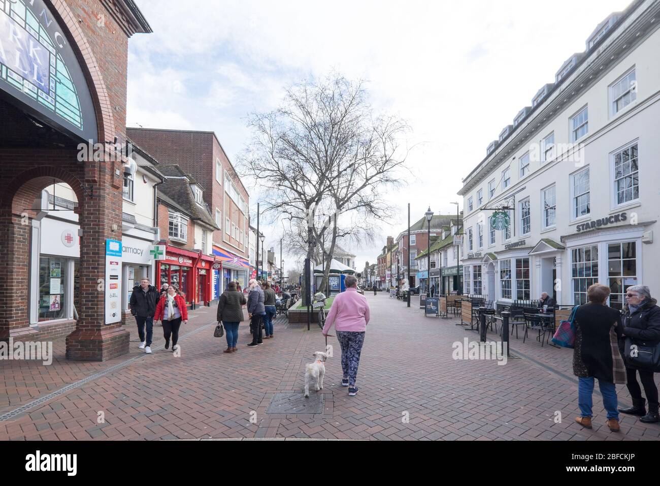 Ashford, Kent, United Kingdom - March 9, 2020: People walking and chatting on High Street in the pedestrianised town centre with shops Stock Photo