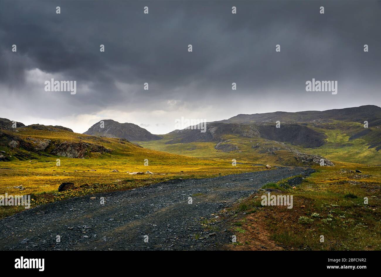 Beautiful landscape with road in the mountain valley at cloudy sky background Stock Photo