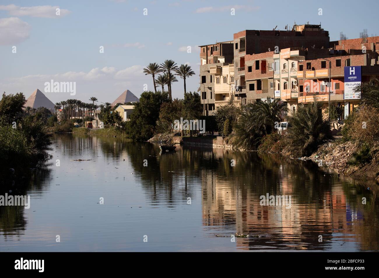 View along a canal near Cairo, Egypt with the Great Pyramids of Giza in the background. Stock Photo