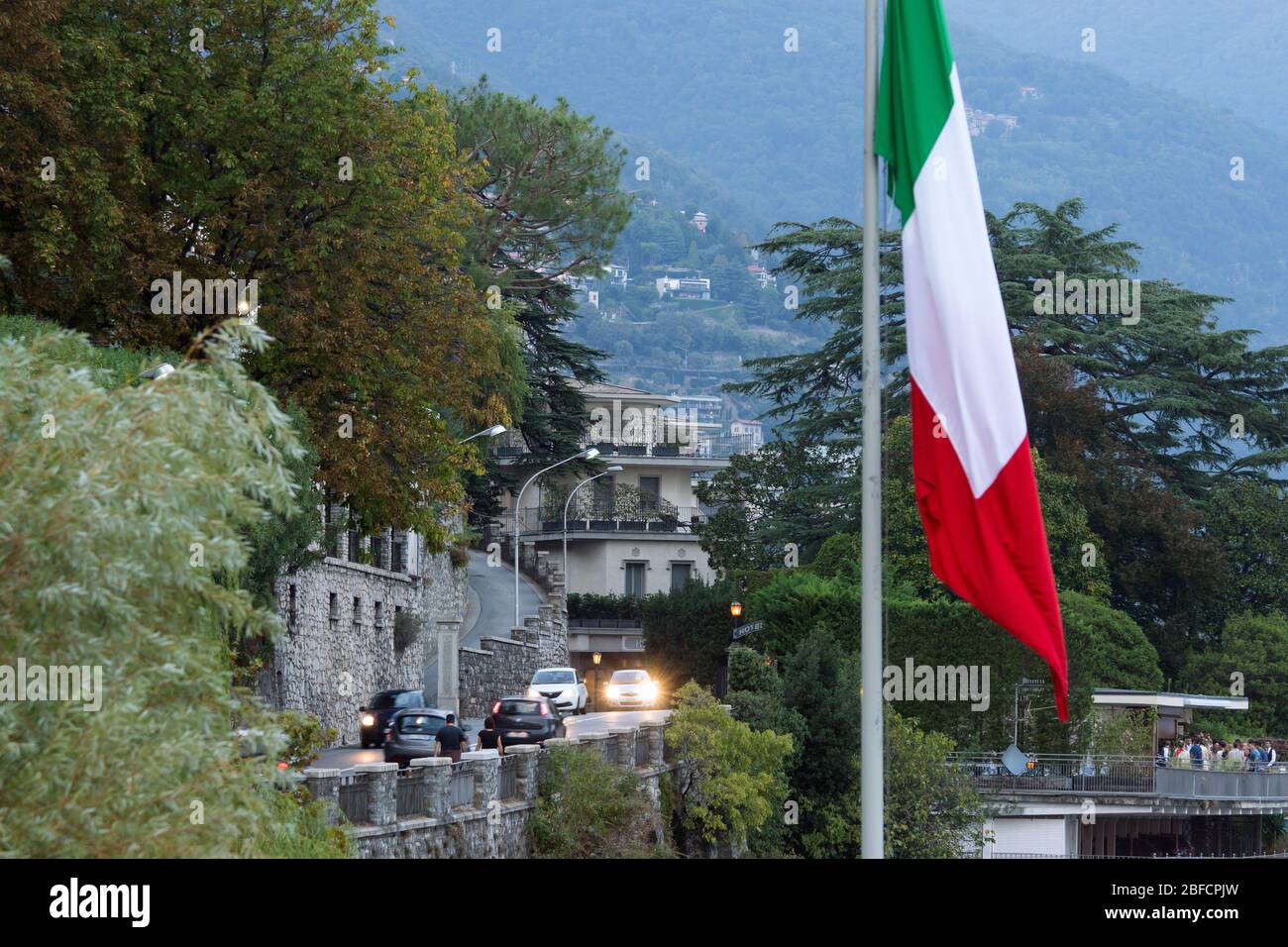 Como, Italy - Sep. 29, 2019 - view to the traffic and village around lake Como. Italian flag at foreground. Stock Photo
