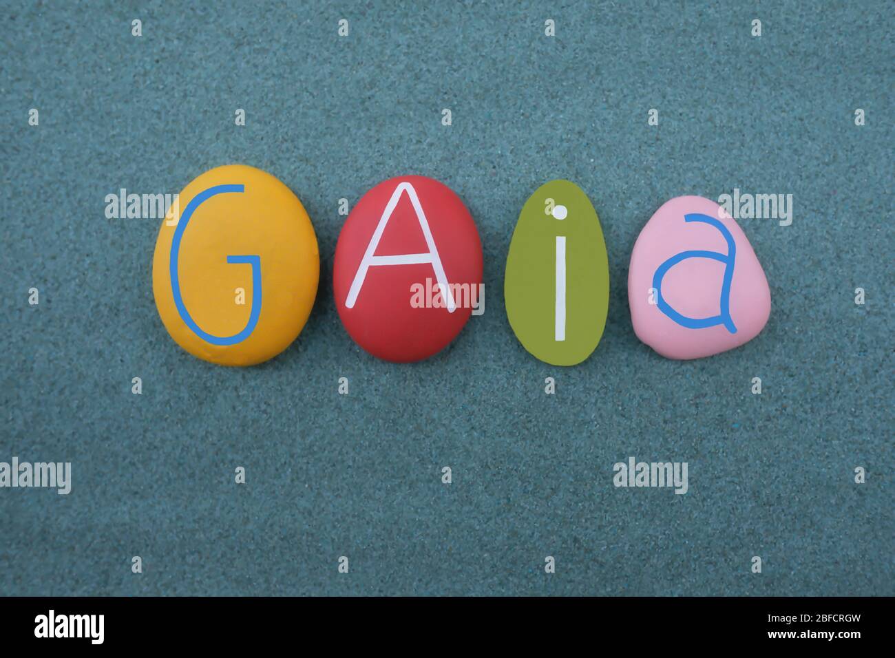 Gaia, female given name composed with multi colored stone letters over green sand Stock Photo