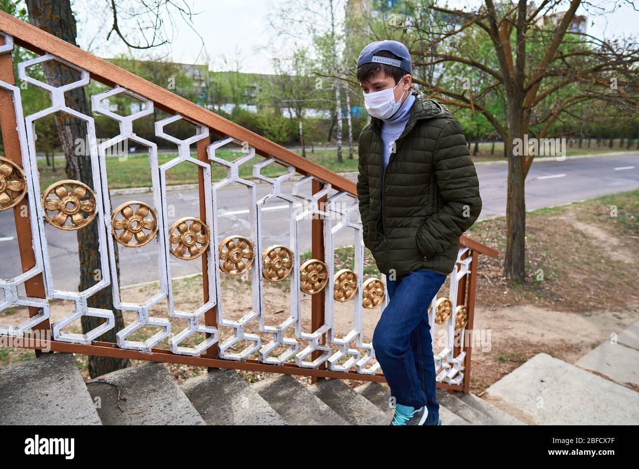 View of teen boy walks down the street during the day, a pedestrian walkway and ...