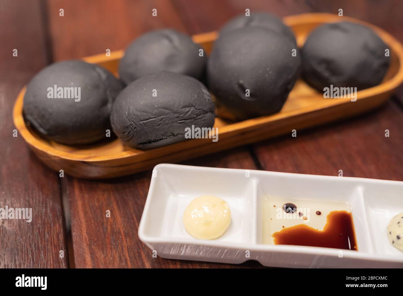Vegetarian bread made with black charcoal bun with mamy sauce on wooden rustic table. Stock Photo