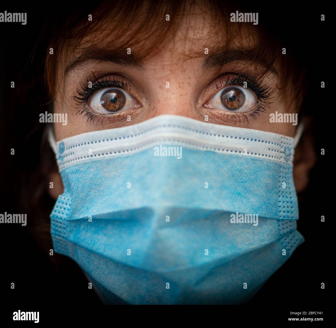 Close up of a scared young woman wearing a medical mask. The new normal worldwide life. Stock Photo