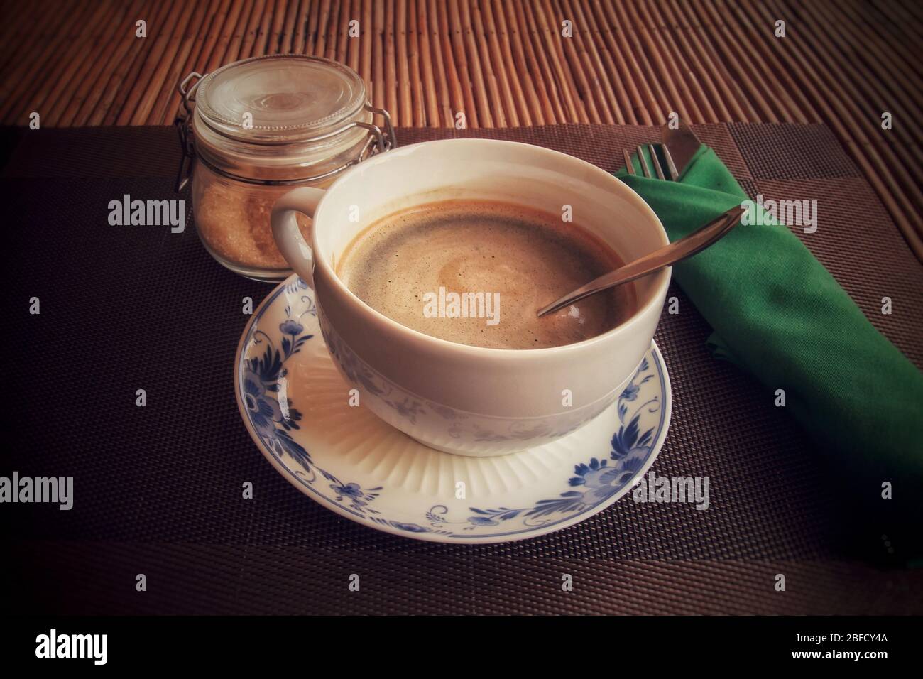 Conceptual photo of a single cup of coffee against a wooden table to show concept of self isolation and social distancing as the new normal Stock Photo