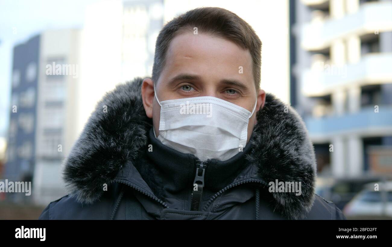 Close up. Man with medical face mask stands at city street