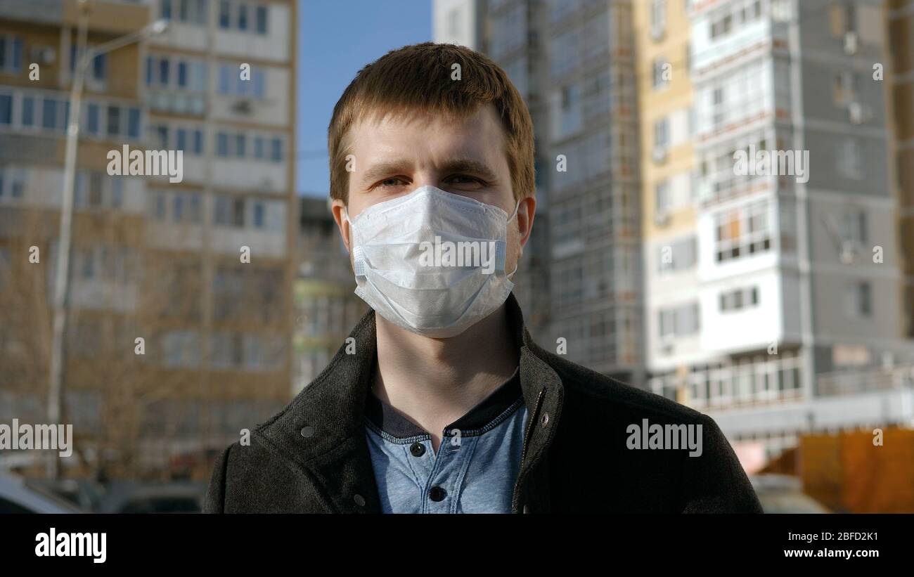 Close up. Man in a surgical mask standing outdoors and looking to camera. Professional shot in 4K resolution. 054. You can use it e.g. in your commerc Stock Photo