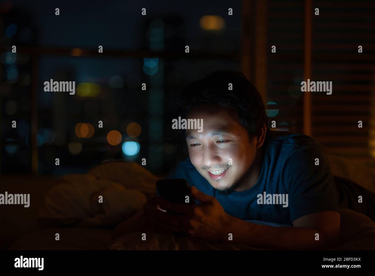 Closeup Asian man sleeping and using smart mobile phone for social network  or video conference call and face time to her lovers on bed over blur city  Stock Photo - Alamy