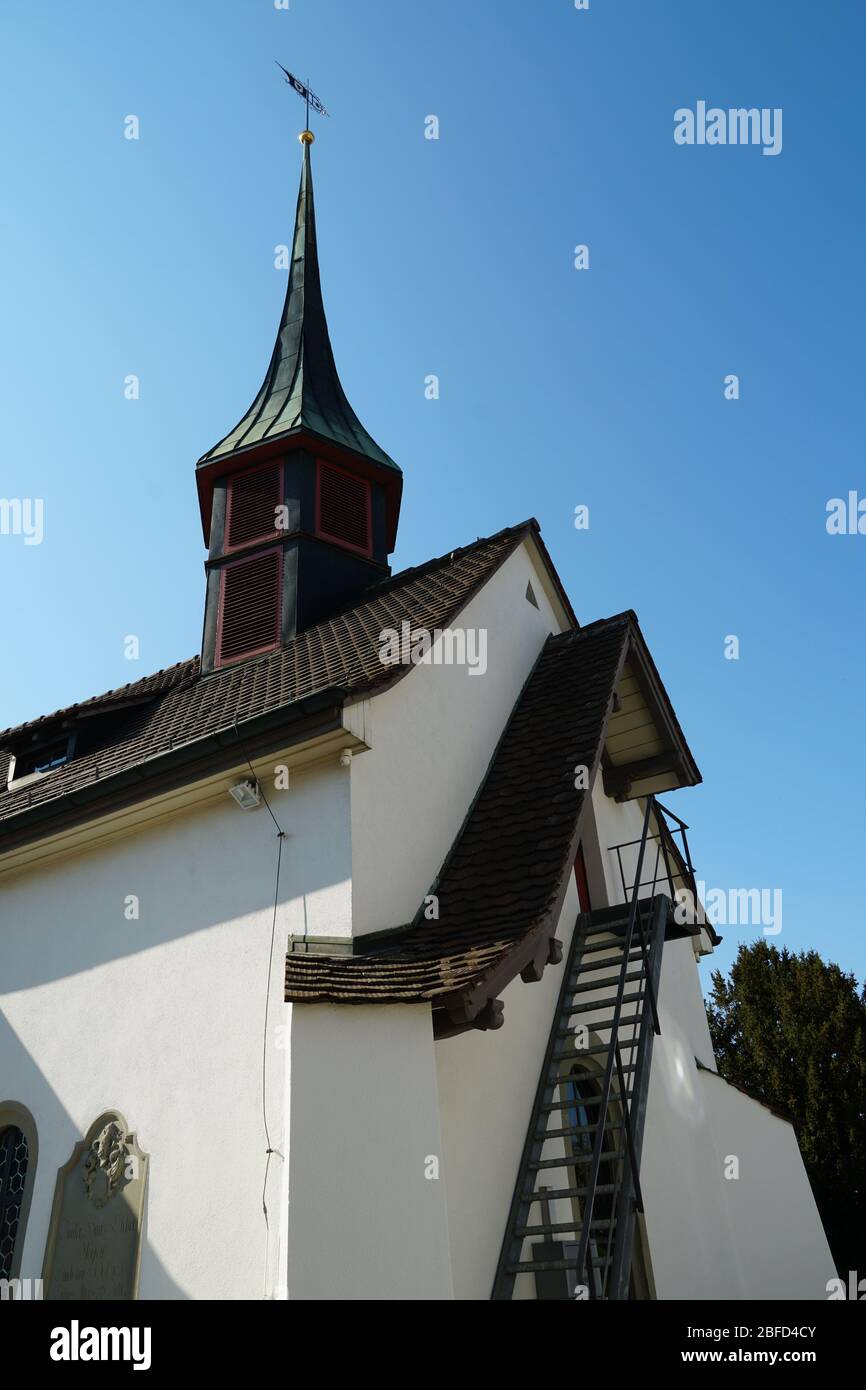 Old reformed church building in Urdorf, Switzerland, lateral view on a clear day, the photo taken in upward perspective with focus on the church tower. Stock Photo