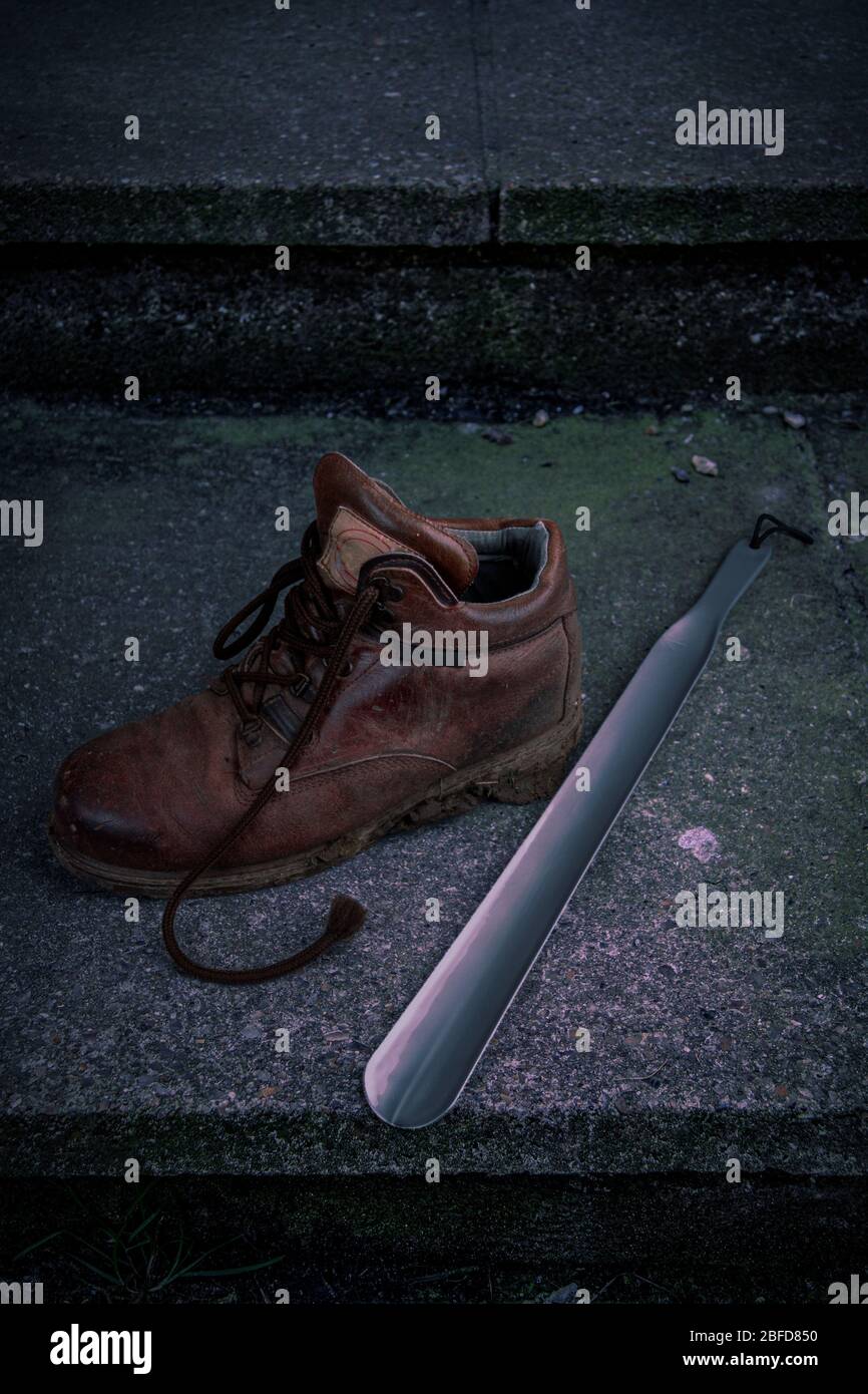 Muddy walking boot and shoehorn Stock Photo
