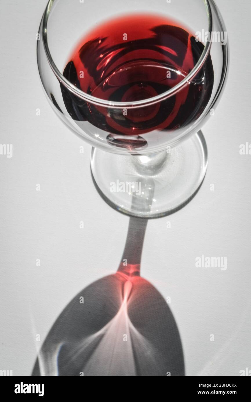 Closeup top view of a glass of red wine with shadows and reflections on a  white textured surface Stock Photo - Alamy