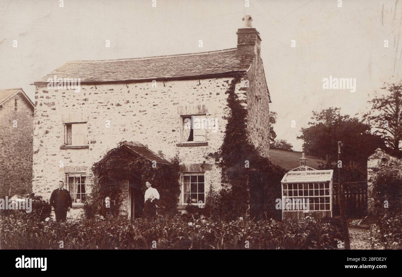 Vintage Early 20th Century British Photographic Postcard Showing a Detached Rural House. Residents Outside The Front of The Property. Stock Photo